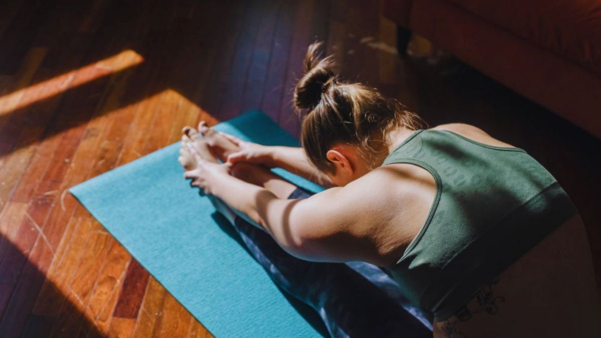 A woman engages in integrative yoga on a mat, basking in sunlight, promoting relaxation and inner peace.
