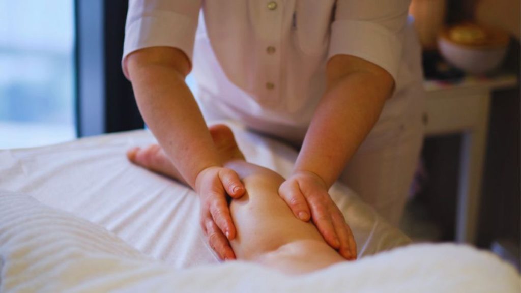 A lymphedema therapist performing a lymphatic drainage massage on a patient's leg to support circulation, reduce swelling, and aid in lymphedema management.