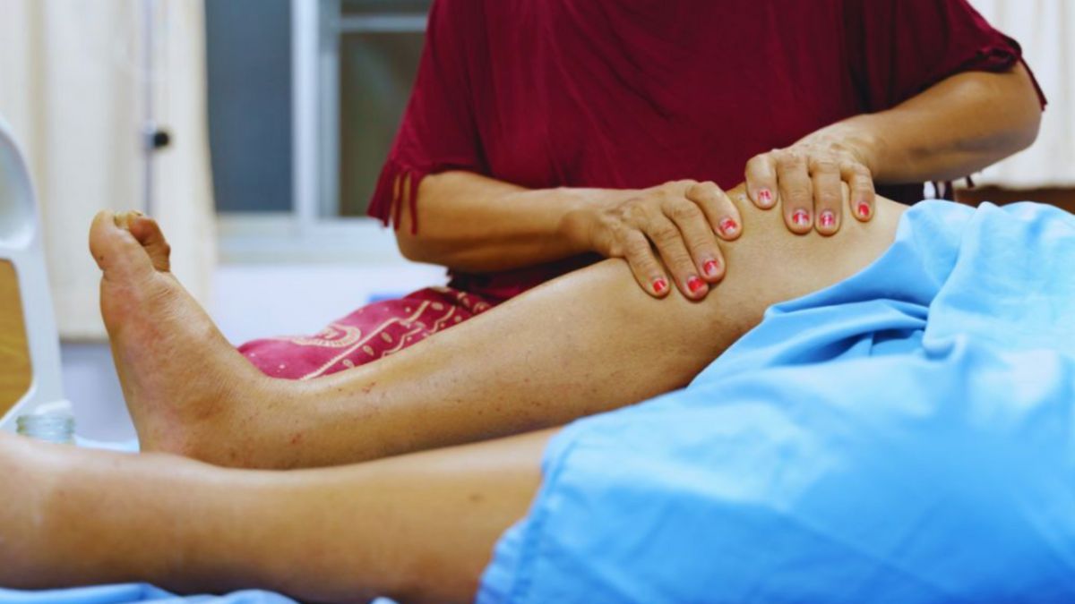 A certified therapist demonstrating manual lymphatic drainage techniques on a patient's leg to help reduce fluid retention and improve circulation.