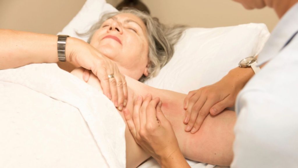 A woman receiving manual lymphatic drainage (MLD) therapy for lymphedema management after breast cancer treatment.