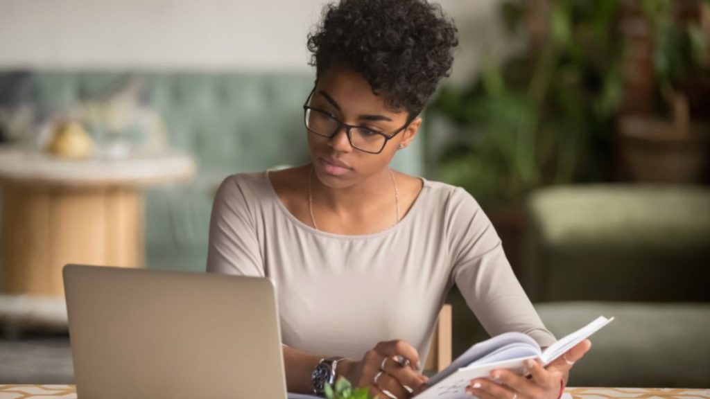 A focused woman in glasses working on her laptop—symbolizing clarity and direction gained through life coaching in Miami.