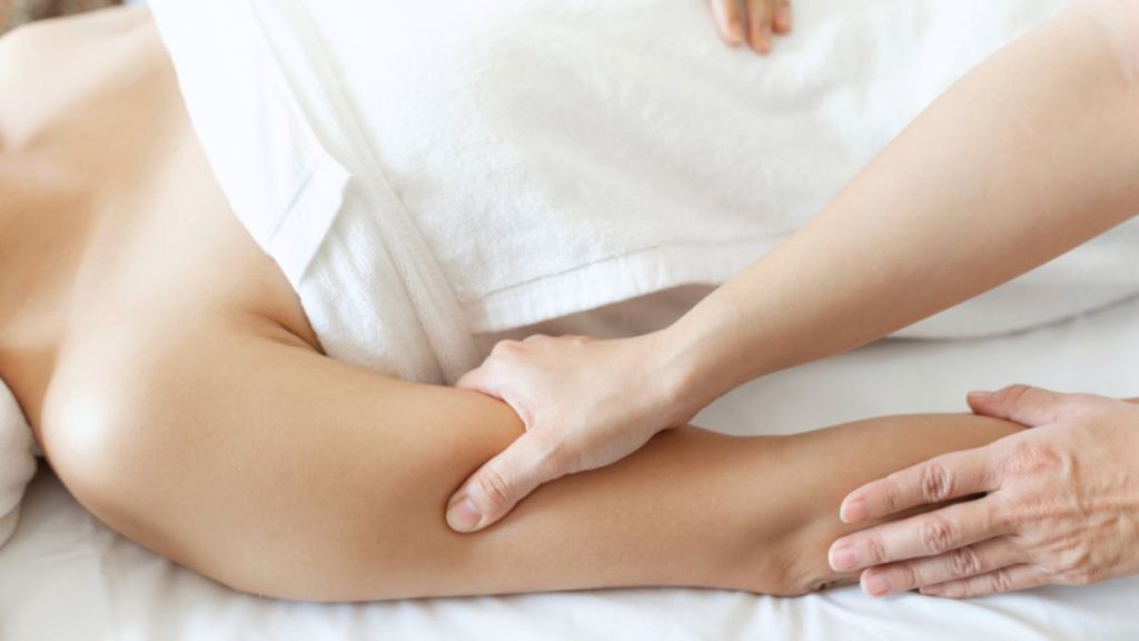 A woman receiving gentle arm massage therapy to reduce swelling and aid recovery after a post-mastectomy surgery.