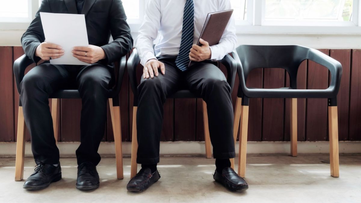 Two men seated with papers and folders discussing career transition coaching at Midas Touch Lymphedema Institute.