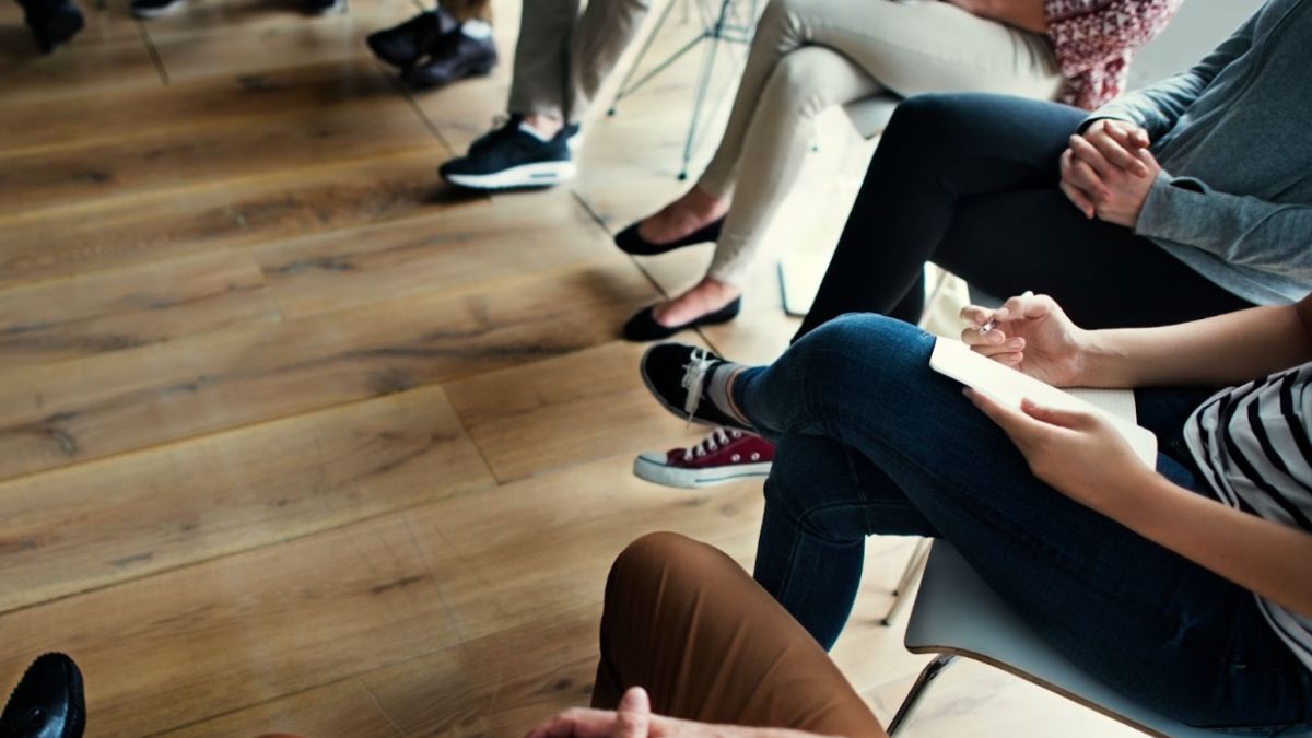 Attendees in a meeting room engaged in a discussion about mindfulness coaching.