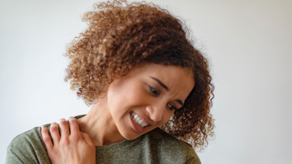 A woman with a sore shoulder in need of a lymph drainage therapist for relief and guidance on managing her pain.