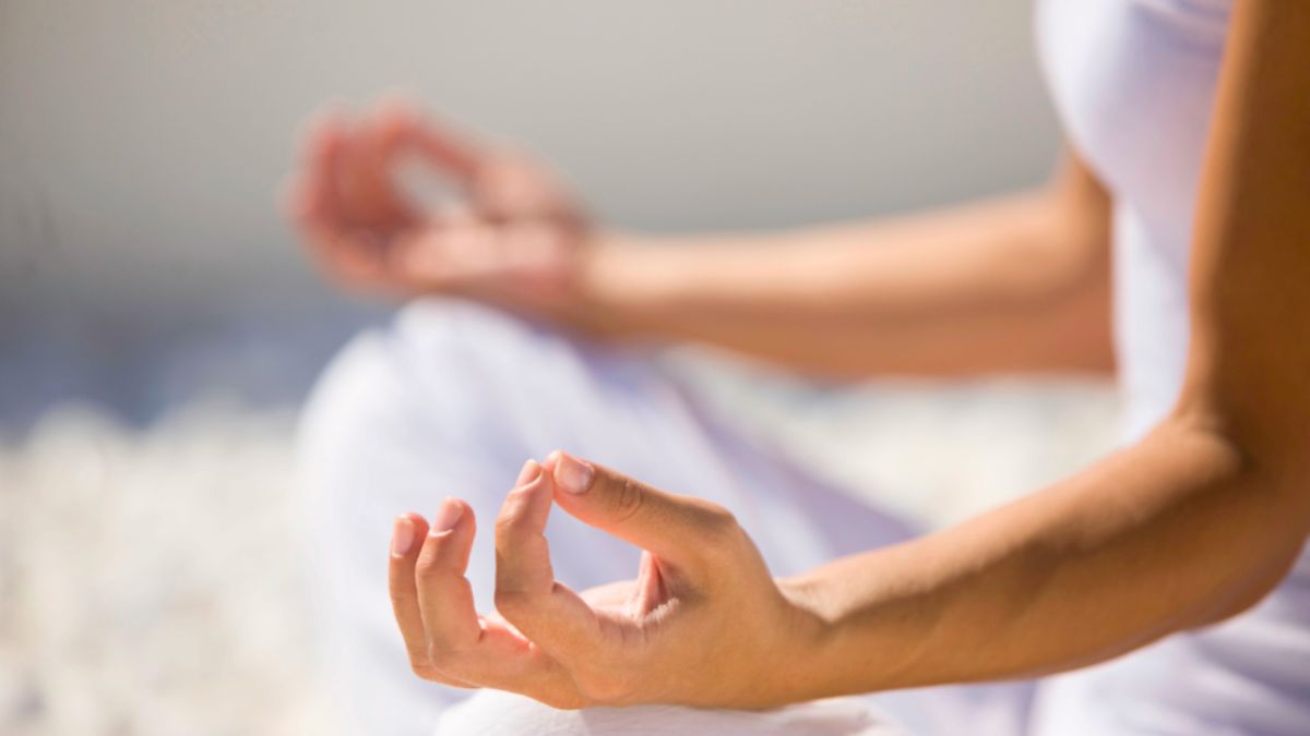 yoga instructor in white is peacefully meditating in a traditional yoga position, promoting mindfulness and calmness.