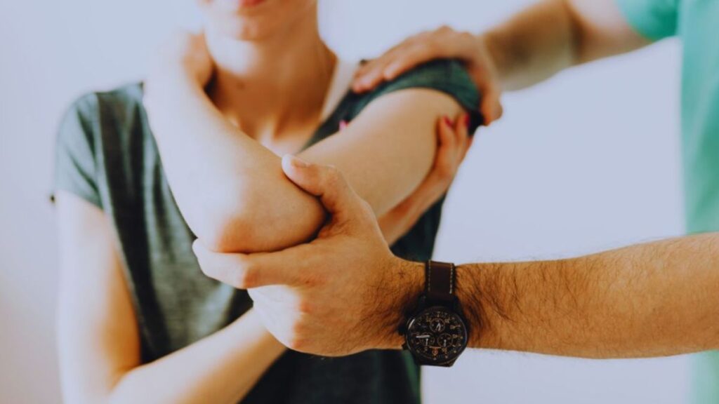 A therapist gently supports and moves a woman's arm during a lymphatic therapy session in Miami, focusing on easing swelling and pain in the shoulder and upper arm.