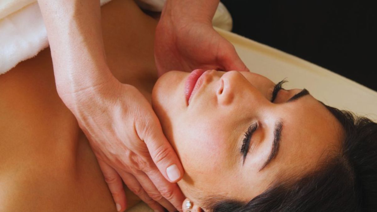 A therapist performs gentle manual lymphatic drainage on a woman's neck and lower face during a lymphatic therapy session in Miami, promoting relaxation and reducing swelling.