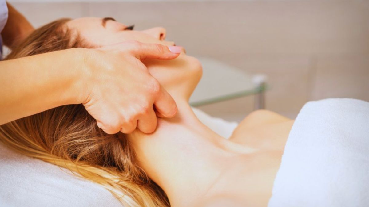 A therapist uses gentle manual techniques on a woman's neck during a lymphatic therapy session, aiming to stimulate lymph flow and promote relaxation.