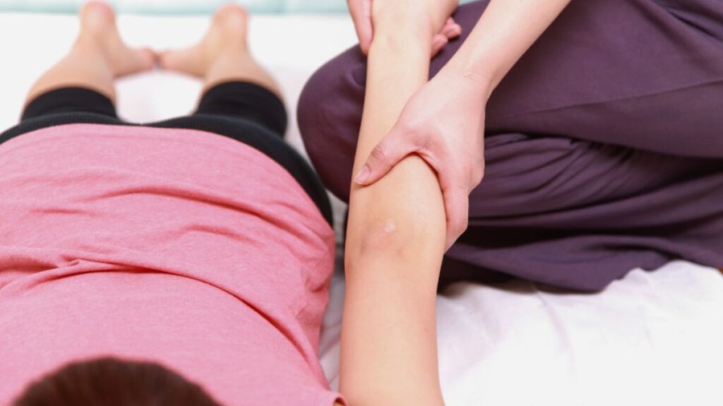 A woman receives lymphedema therapy from a therapist during a massage session in a calming environment.